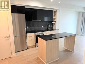 Toronto (Clanton Park) condo for rent - A modern kitchen with wooden cabinets and a black countertop.