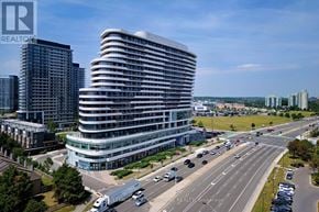 Mississauga (Central Erin Mills) condo for rent - A modern multi-story building with a curved facade is the focal point of a busy intersection with vehicles and other buildings in the background.