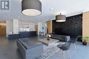 Mississauga (Central Erin Mills) condo for rent - A modern living room with a grey sofa, a grey armchair, a grey coffee table, and a black wall with a pattern of small lights.