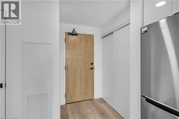 Brantford condo for rent - A modern kitchen with a wooden door and a stainless steel refrigerator.