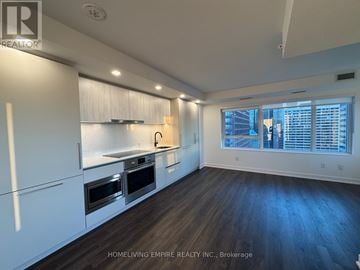 Toronto (North St. James Town) condo for rent - A kitchen with white cabinets and a window with blinds.