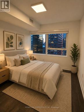 Toronto (North St. James Town) condo for rent - A bedroom with a large bed and a window overlooking a cityscape.