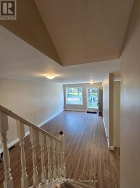 London East (East I) apartment for rent - A hallway with wood floors and white railings leading to a door.