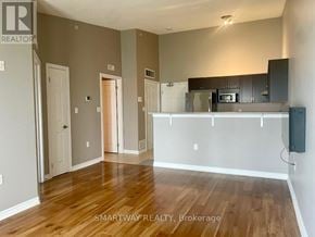 Milton (De Dempsey) condo for rent - A room with wooden floors and a kitchen area with a microwave and oven.