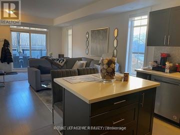 Vaughan (Islington Woods) townhouse for rent - A modern kitchen with a large island and a living area with a couch and chairs.