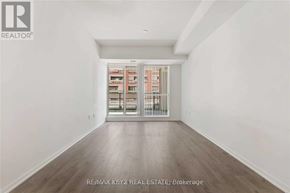 Toronto (Yorkdale-Glen Park) condo for rent - A room with a white wall and a wooden floor leading to a hallway with a glass door.