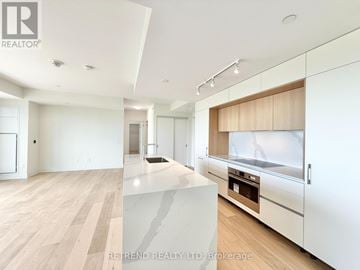 Toronto (Annex) condo for rent - A modern kitchen with white cabinets and a wooden island.