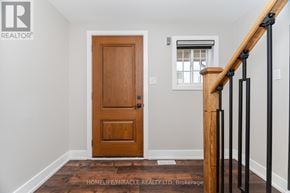 Barrie (Georgian Drive) townhouse for rent - A wooden door is in a white room with a staircase.
