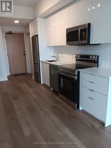 Brantford condo for rent - A kitchen with white cabinets and a black stove top oven.