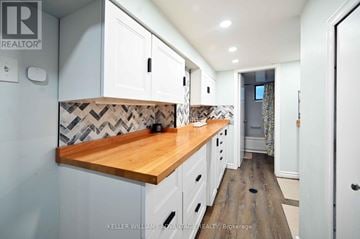 Toronto (Woodbine-Lumsden) apartment for rent - A kitchen with white cabinets and a wooden counter top.