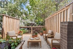 Oakville (Co Central) townhouse for rent - A wooden deck with chairs and a table surrounded by greenery.