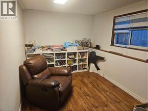 Coquitlam apartment for rent - A living room with a brown leather chair and a bookshelf filled with books.