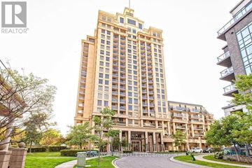 Toronto (Bayview Village) condo for rent - A tall building with a balcony on the top floor is surrounded by greenery and a clear sky.