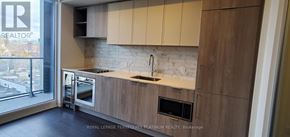 Toronto (Humewood-Cedarvale) condo for rent - A kitchen with a white brick backsplash and wooden cabinets.
