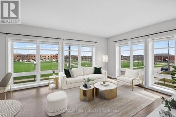Kitchener condo for rent - A well-lit, spacious living room with white furniture and a view of a park outside the windows.