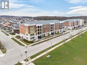 Kitchener condo for rent - A large building with a red brick facade is surrounded by a grassy area and a road.
