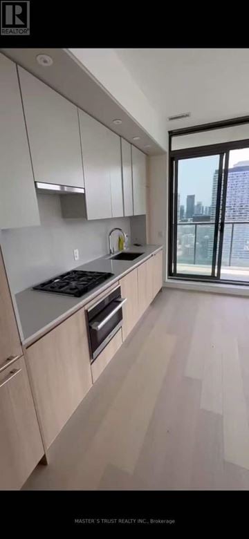 Toronto (Church-Yonge Corridor) condo for rent - A kitchen with wooden cabinets and a stove top oven.