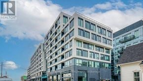 Oakville (Wm Westmount) condo for rent - A modern multi-story building with a glass facade is the main focus of the image.