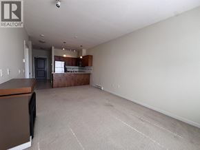 Pitt Meadows apartment for rent - A large empty room with a kitchen area in the background.