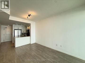 Toronto (Niagara) condo for rent - A spacious room with a kitchenette in the background.