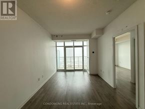 Toronto (Niagara) condo for rent - A spacious room with wooden floors and a large window.