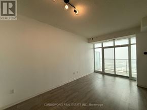 Toronto (Niagara) condo for rent - A large empty room with a sliding glass door leading to a balcony.