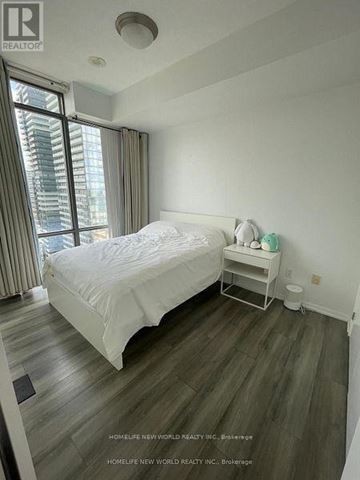 Toronto (Bay Street Corridor) condo for rent - A bedroom with a large bed and a window with curtains.