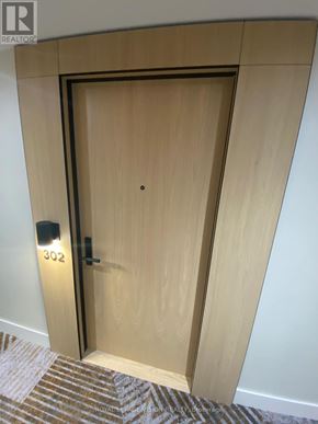 Toronto (Englemount-Lawrence) condo for rent - A wooden door with a black handle and a number 302 on the wall.
