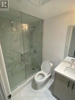 Toronto (Englemount-Lawrence) condo for rent - A white toilet with a glass shower stall in the background.