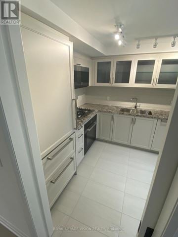 Toronto (Englemount-Lawrence) condo for rent - A kitchen with white cabinets and a white tile floor.