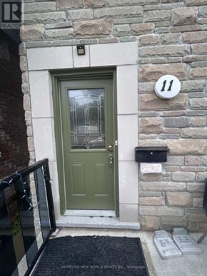 Toronto (Rockcliffe-Smythe) apartment for rent - A green door with a glass window is on a stone wall with a number 11 on it.