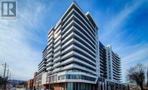 Hamilton (Beasley) condo for rent - A tall, modern building with many windows and balconies is shown under a clear blue sky.