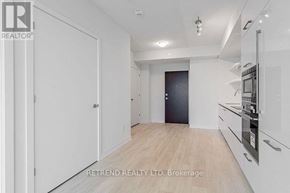 Toronto (Mount Pleasant West) condo for rent - A white kitchen with wooden floors and a black door.