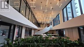 Oakville (Jm Joshua Meadows) condo for rent - A modern atrium with glass walls and hanging lights.