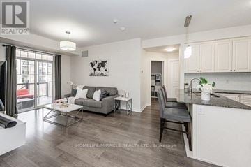 Oakville (Ro River Oaks) townhouse for rent - A well-lit, modern kitchen and living room with a grey sofa and a coffee table.