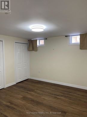 Kitchener apartment for rent - A room with wood flooring and two windows with curtains.