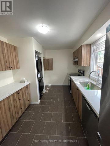 Kitchener apartment for rent - A kitchen with brown cabinets and a black refrigerator.