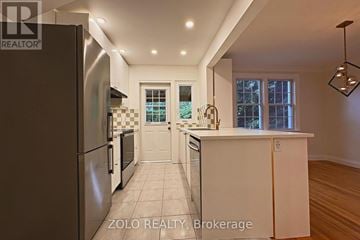 Ottawa apartment for rent - A modern kitchen with a refrigerator on the left and a countertop with a window in the background.