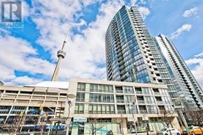 Toronto (Waterfront Communities) condo for rent - A modern glass building stands tall next to a smaller building with a tower in the background.