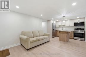 Guelph (Kortright Hills) apartment for rent - A well-lit, modern kitchen and living room with a beige sofa and wooden flooring.