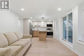 Guelph (Kortright Hills) apartment for rent - A well-lit, modern kitchen and living room with a beige sofa.