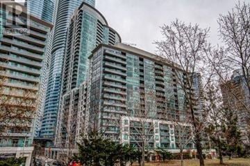 Toronto (Waterfront Communities) condo for rent - A modern building with glass windows and balconies is surrounded by bare trees.