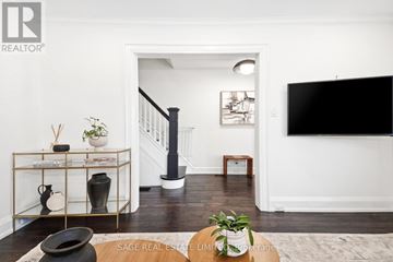 Toronto (East York) apartment for rent - A living room with a black sofa and a TV on the wall.