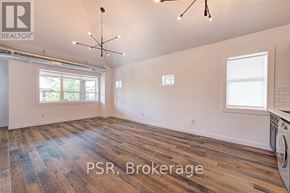 Toronto (The Beaches) multi-family for rent - A large, empty room with wood flooring and a washing machine in the corner.