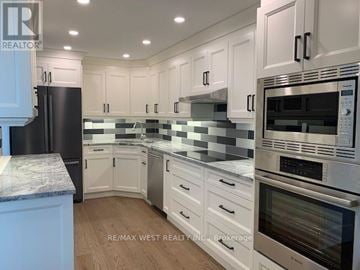 Toronto (Markland Wood) condo for rent - A kitchen with white cabinets and a black refrigerator.