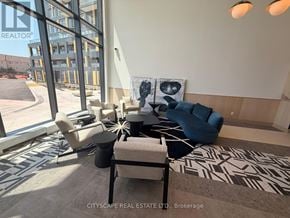 Burlington (Alton) condo for rent - A living room with a large window and a view of a parking lot.