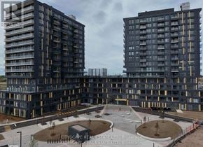 Burlington (Alton) condo for rent - Two large buildings with balconies and a courtyard in front.