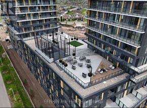 Burlington (Alton) condo for rent - A construction site with a building under construction and a parking lot in the foreground.