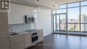 Toronto (University) condo for rent - A kitchen with a microwave, sink, and oven with a view of the city.