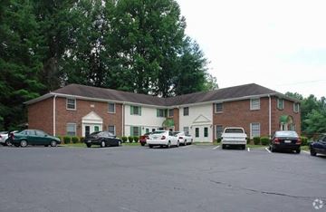 Winston-Salem apartment for rent - A parking lot in front of a brick building with cars parked.